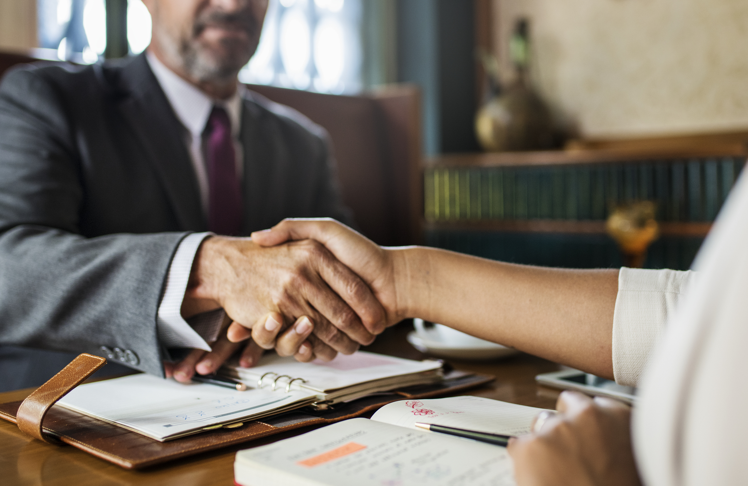 A man and woman shake hands at a desk, finalizing the booking  an airport taxi.