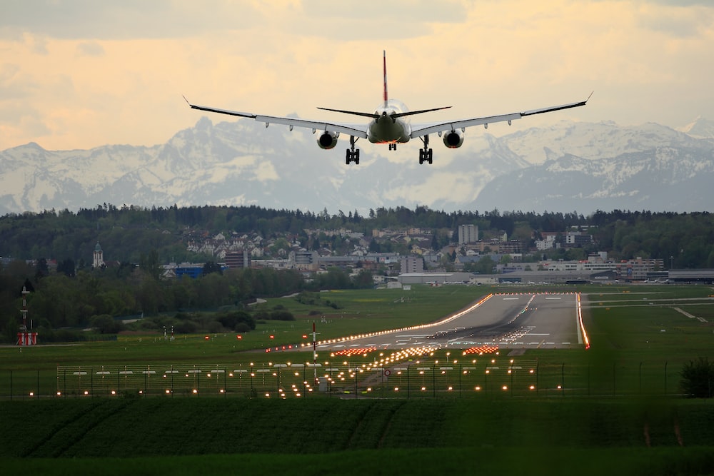 A plane lifts off from an airport runway, leaving the airport taxi area behind as it ascends into the sky