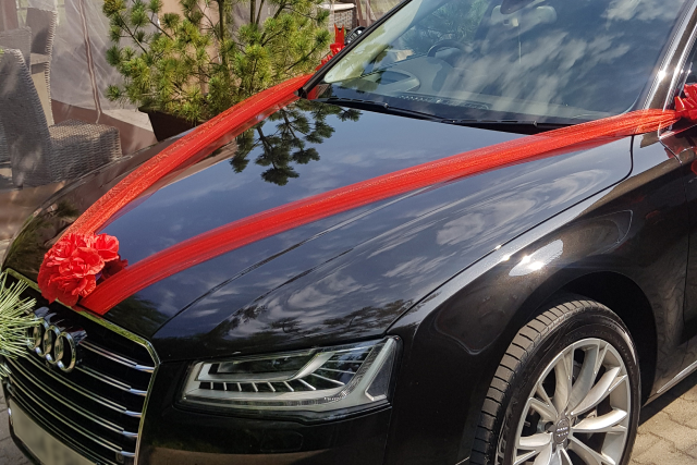 A sleek black luxury car adorned with red ribbons, ideal for Liverpool Airport taxi service