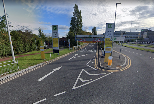 Entrance to the drop-off zone at Manchester Airport's Terminal 1, with clear road markings and signs guiding drivers. Ideal for convenient airport taxi booking services